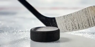 Close up of a hockey stick and puck on an ice rink surface