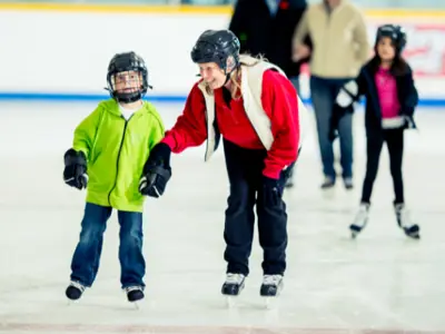 Family with children skating on an indoor ice rink.