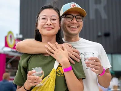 Two attendees smile for a photo while holding drinks and standing arm-in-arm at Flow Fest in 2025.