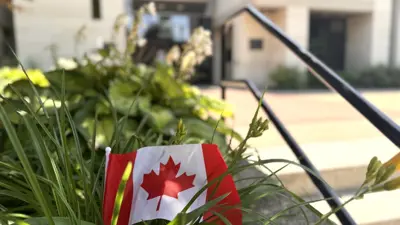 Small Canada Flag in the garden in front of City Hall in Niagara Falls.