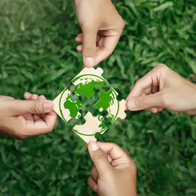 Four hands putting puzzle together over grass