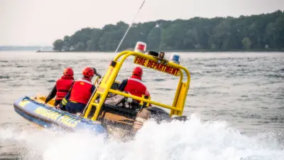 Photo of the City of Niagara Falls Fire Department rescue boat moving on the water with three people on board.