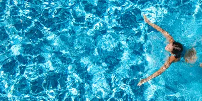An individual swimming in a blue swimming pool
