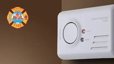 Carbon monoxide alarm on a brown wall.