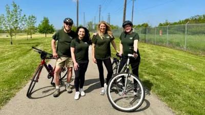 Four people posing with their bikes on a recreational trail.