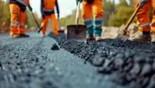 Image of construction workers putting new asphalt on a road.