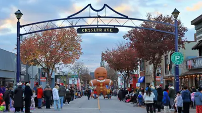 City of Niagara Falls Santa Claus Parade. Showing the parade coming towards Chrysler Avenue. Crowds are gathered on each side of the street. An inflatable gingerbread cookie is in the background.