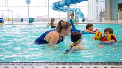 The MacBain Community Centre indoor pool. A swimming lesson instructor is in the water talking to three young children