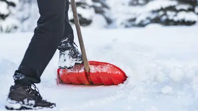 Person with a red shovel clearing snow
