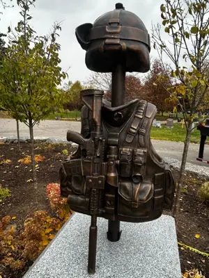 A bronze casting memorial of a soldiers vest, headpiece and gun.