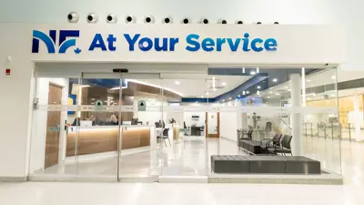 Image of the entrance of the At Your Service Niagara Falls customer service room at the MacBain Community Centre. Showing the City logo and name at the top and glass doors and windows. The service counter is inside the room in the background.