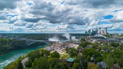 View of Niagara Falls and river with city buildings and bridge.