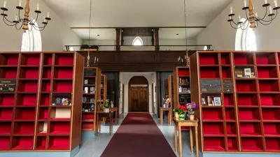 The Stamford Green heritage columbarium located inside the church. Showing a maroon carpet down the middle isle with niches on each side like a book case with red velvet interiors.