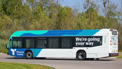 Blue, aqua and white Niagara Transit bus on roadway with message "We're going your way"