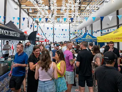 Flow Fest Niagara event with people visiting vendor booths inside the Exchange Market Hall.