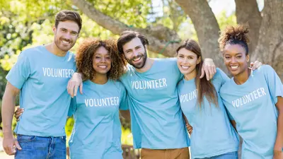 A group of five volunteers wearing matching blue shirts with the word "Volunteer" in white text on the shirt. They are smiling for the camera.