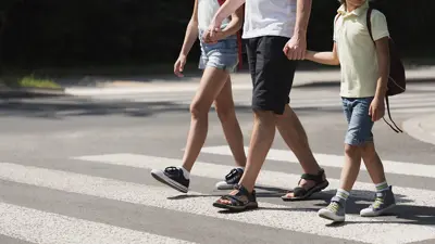 Three people walking across a pedestrian crosswalk