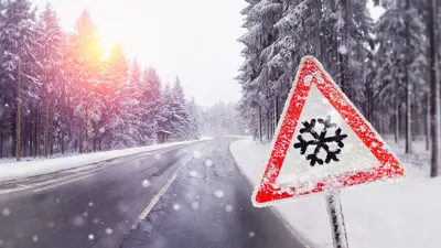 Snow fall warning sign at snowy roadside