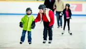 Family with children skating on an indoor ice rink.