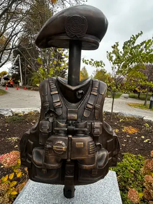 A bronze casting of a soldiers vest, binoculars, and hat.